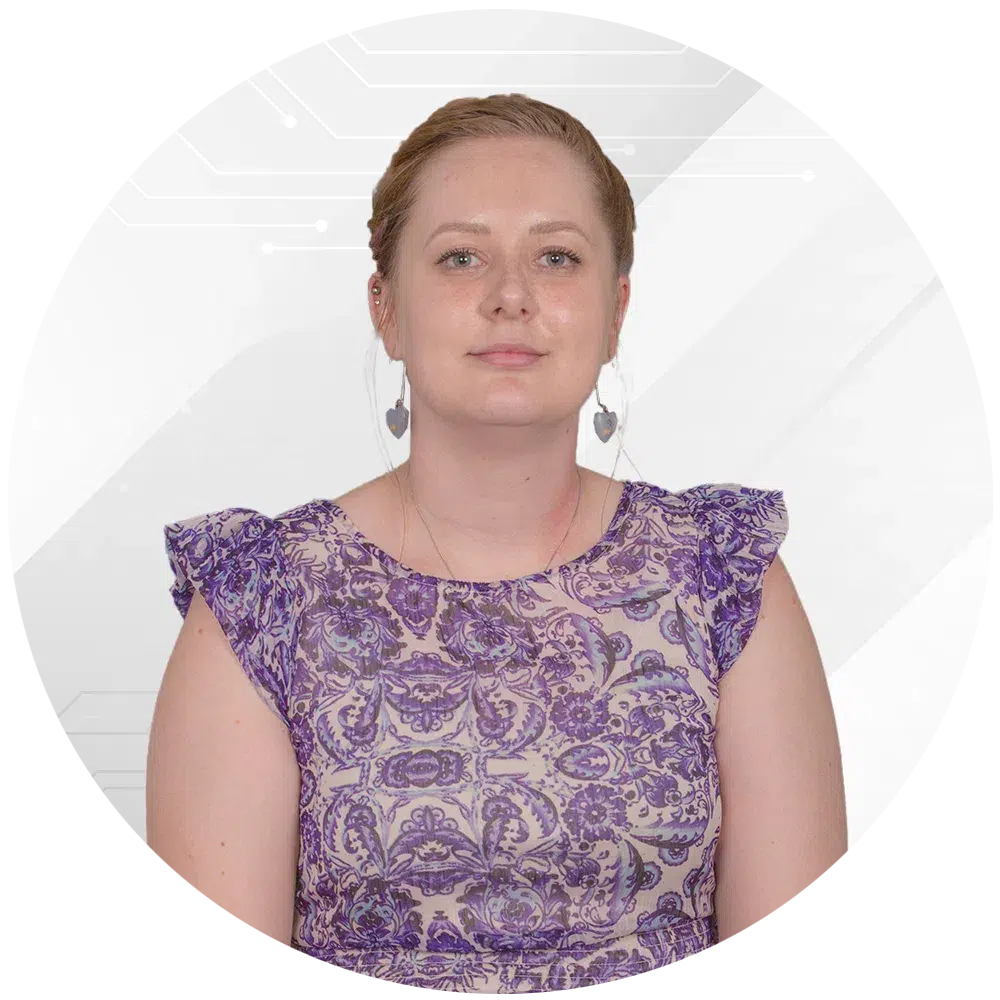 Portrait of a woman with light brown hair tied back, wearing a purple patterned lace dress and heart-shaped earrings, looking at the camera against a white abstract background.