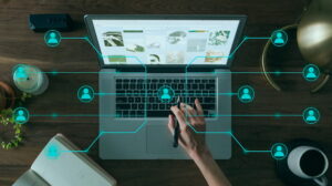 Overhead view of a person using a laptop at a wooden desk, surrounded by glowing blue digital network connections and user icons representing AI literacy and governance.