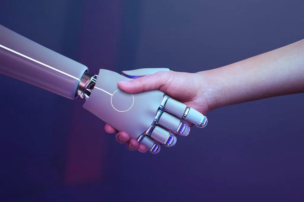 Robotic and human hands shaking, symbolizing collaboration and the strategic value of Studying AI in today’s technology-driven world.