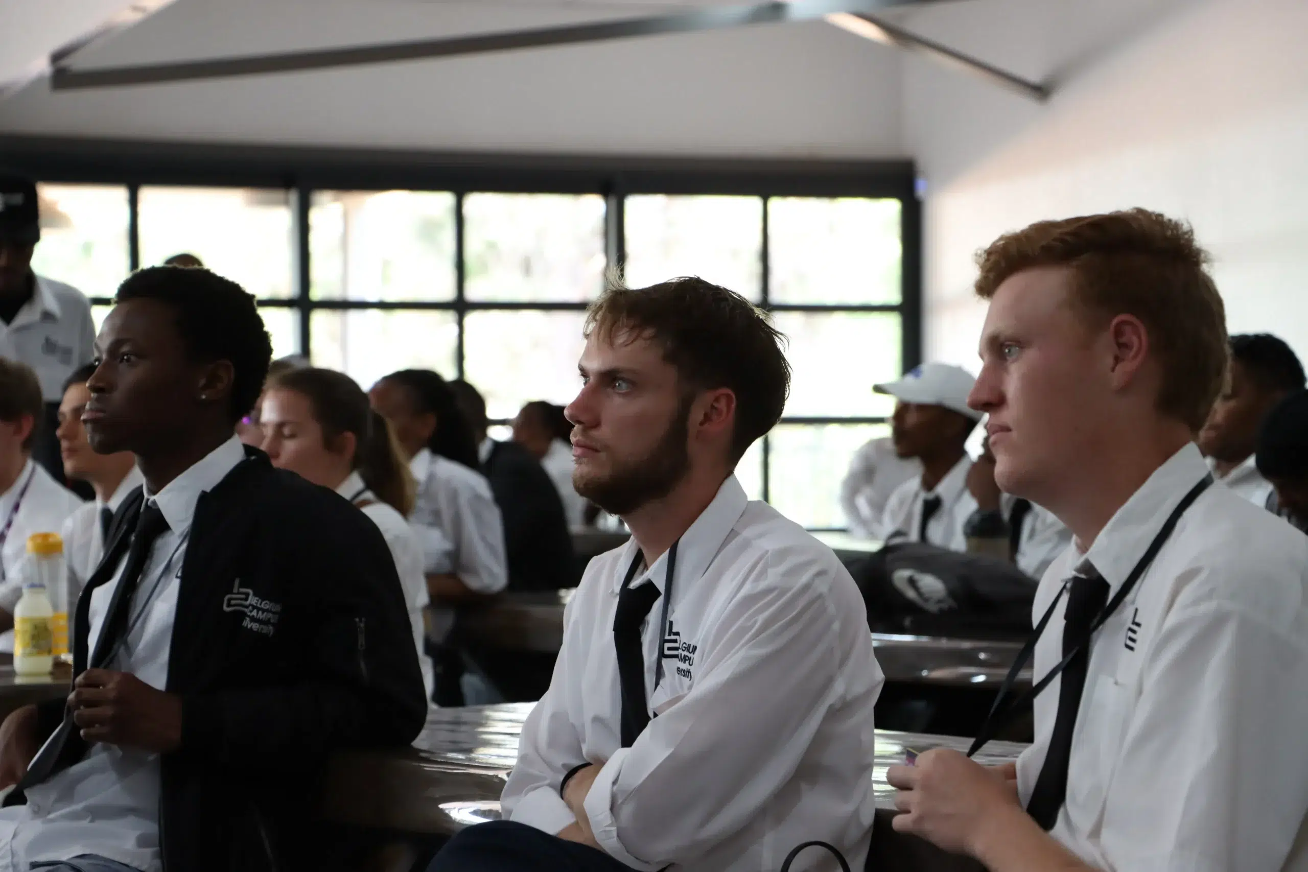 Group of students in white shirts and black ties seated in a classroom, attentive during a lecture