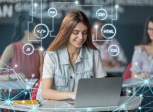 Students sit in a classroom working on laptops, with one student in the foreground focused on coding. Overlaid digital graphics show icons and labels for programming technologies such as PHP, HTML, CSS, JavaScript, and DEV, connected by lines and nodes to represent the relationships between different web development tools.