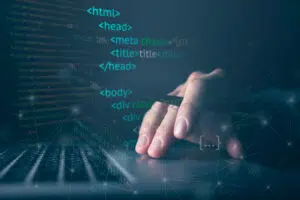 Close-up of a hand using a laptop touchpad, overlaid with HTML and web development code elements such as , , , and tags. The image has a blue-toned digital design with network connection graphics, symbolising software development, coding, web design, and technology.