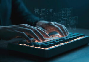 Hands typing on a computer keyboard, overlaid with digital screens displaying code, graphs, data and world maps, representing software development and data technology.