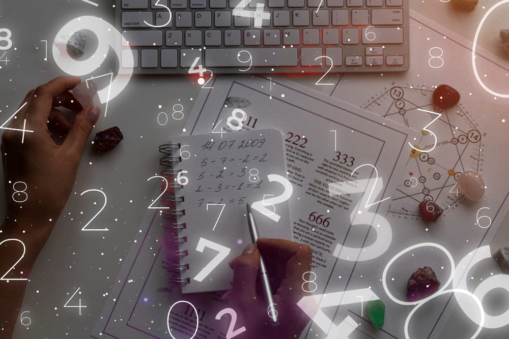 Person working on mathematical calculations in a notebook with charts, crystals and a keyboard, overlaid with floating numbers to represent numerology, data analysis and pattern discovery.